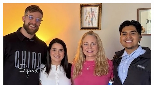 Dr. Nicole Shutko with blonde hair and a pink shirt standing with her team in the office